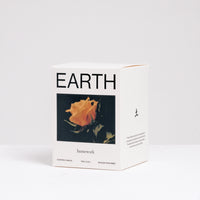 The branded box of an Earth-scented candle featuring an image of an orange rose, made by Homework and available at NiMi Projects UK.