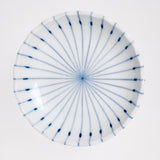 A top view of a white, Japanese porcelain, Mino-yaki pinstriped side dish, showcasing its gently fluted lip and a design of radial thin lines in blue underglaze. Available at NiMi Projects UK.