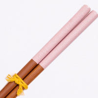 A closeup image of a pair of wooden Japanese chopsticks with textured ends in dusty pink. Available at NiMi Projects UK.