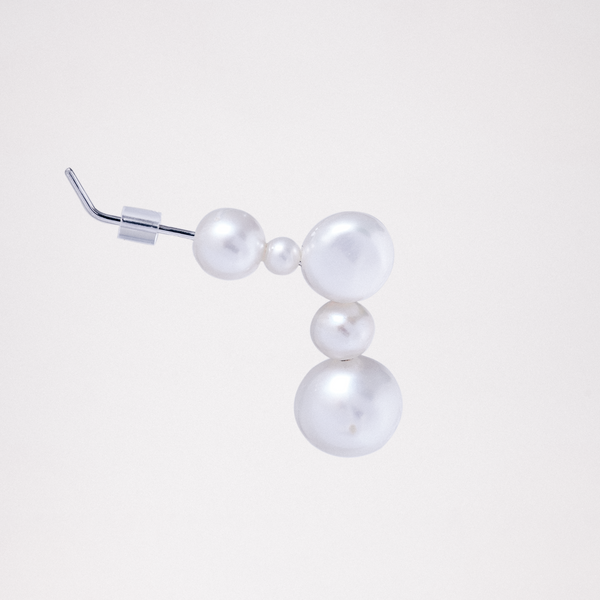 A side view of a Pokoko 5-pearl stud earring, made by Onomatopee, featuring a small freshwater pearl, tiny pearl and another large pearl at the top of the earring, and two more pearls dropping below them. Post is silver. Available at NiMi Projects UK. 