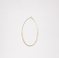 A side image of a gold vermeil, small Onomatopee Puchipuchi Hoop Earring, featuring a row of tiny dots along the bottom section of the hoop and 3 cm in diameter. On show at NiMi Projects UK.