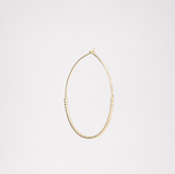 A side image of a gold vermeil, small Onomatopee Puchipuchi Hoop Earring, featuring a row of tiny dots along the bottom section of the hoop and 3 cm in diameter. On show at NiMi Projects UK.