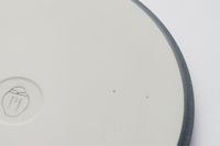 The base of a Kihon no Utsuwa Japanese porcelain dinner plate, showcasing the brand’s original logo imprinted in its center.