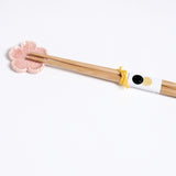 A pink sakura (cherry blossom) shaped Japanese, Mino-yaki hashioki chopstick rest, with a pair of bamboo chopsticks. Available at NiMi Projects UK.