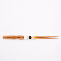 A pair of twisted bamboo chopsticks featuring a NiMi Projects logo label and tied with yellow twine.