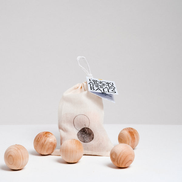 A set of five NiMi Projects Hinoki (Japanese Cypress) wooden aromatherapy balls on display with a natural coloured cotton bag branded with the NiMi Projects logo of two circles — one in black, the other an outline. Made in Japan by Hoshino Kyoto from thinned forest wood.