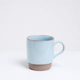 A pastel blue glazed Mino-yaki, Japanese porcelain, stacking mug, featuring an unglazed base and lip.On show at NiMi Projects UK.