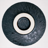 An ariel view of the base of a ceramic Japanese matcha tea chawan bowl showcasing its black glaze accented with a subtle shimmer and the unglazed foot. Available at NiMi Projects UK.