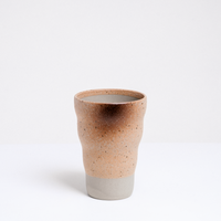 A Mino-yaki, Shigaraki style, Japanese pottery tumbler, featuring a raw clay base and a top glaze in creamy yellow that is naturally speckled and singed during the firing process. On show at NiMi Projects UK.