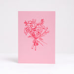 A pink greeting card designed by Takako Copeland and available at NiMi Projects, featuring a letter-pressed printed illustration of a bouquet of flowers in red.