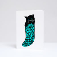 A Takako Copeland illustrated and letterpress printed Christmas cards, available at NiMi Projects UK, featuring a black cats in a green knitted stockings. 