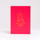 Designed and letter-press printed by Takako Copeland, the Kitty Hug card is red and features an illustration in yellow of a parent cat giving a kitten a warm all-embracing hug.