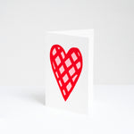 A standing, white Valentines card, designed by Takako Copeland, featuring her illustration of a large, red and pink checked heart. Availaible at NiMi Projects UK.