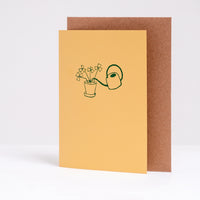  A letterpress printed greeting card by Takako Copeland,  displayed with its brown envelope, featuring green illustration of a potted Oxalis plant and a watering can. Available at NiMi Projects.