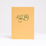  Letterpress printed in green on bright yellow, Takako Copeland's Oxalis Card features an illustration of a bundle of Oxalis growing tall as they are watered by a long-spout watering can.