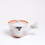 A vintage Japanese Hagi-yaki, rustic-style yokode (side-handled) teapot, made with an orange clay base and decorated with white drip glaze. Available at NiMi Projects UK.