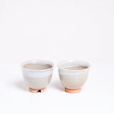 Two Hagi-yaki, rustic-style ceramic Japanese teacups, featuring an orange clay base and white and white drip glaze. Available at NiMi Projects UK.