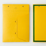 An top view of two Postalco Snap Pocket envelopes in mustard yellow, featuring holes at the top to attach to a Snap Pad. One side is lined and features the Postalco bird logo at the top, the other side is plain yellow with a dark green border.