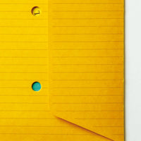 A detail image of the Postalco Snap Pocket envelope, showcasing its yellow, lined exterior and two small holes to reveal its contents.