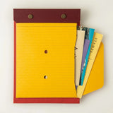 A top view of a small Postalco Snap Pocket envelope attached to a Postalco A6 Snap Pad in red.