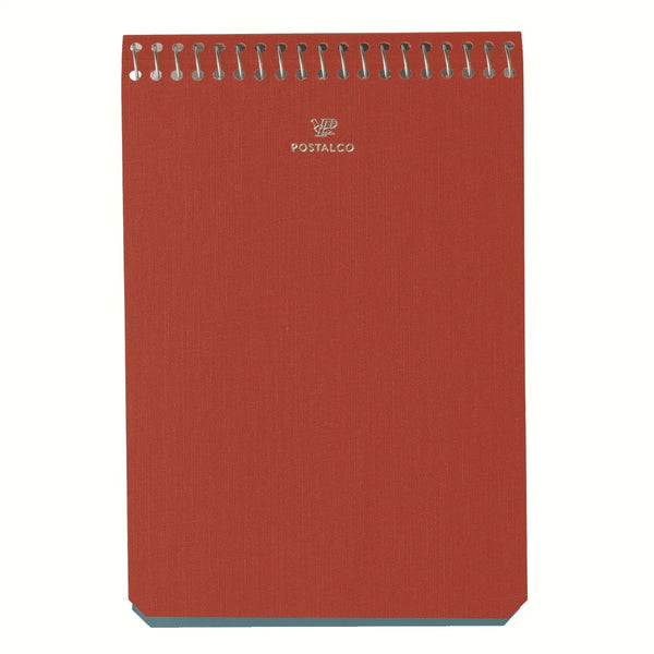 A top image of a Postalco A6 Note Book in signal red, with a spiral top and featuring the Postalco bird logo debossed in gold.