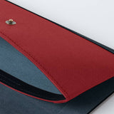 A detail image of an open Postalco Snap Pen Case with a navy blue soft, cow-hide back section and red cotton textile front section with a metal snap clasp.