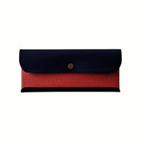 A Postalco Snap Pen Case with a navy blue soft, cow-hide top with metal snap clasp and red cotton textile central section.