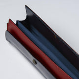 A detail image of an open Postalco Tool Box pen case, showing its pockets and its navy blue, soft, cowhide leather top with metal snap clasp and central red and blue, inner cotton textile.