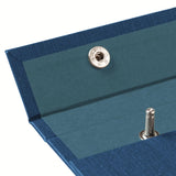 A detail image of the top left of a lake blue fabric-covered Postalco Snap Pad, showing a dark blue interior textile and an open metal snap clasp.