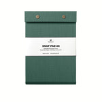 A dark green pressed-cotton covered Postalco Snap Pad, showing the two roundmetal snap clasps at its top and a white label wrapped around its center featuring the Postalco bird logo.